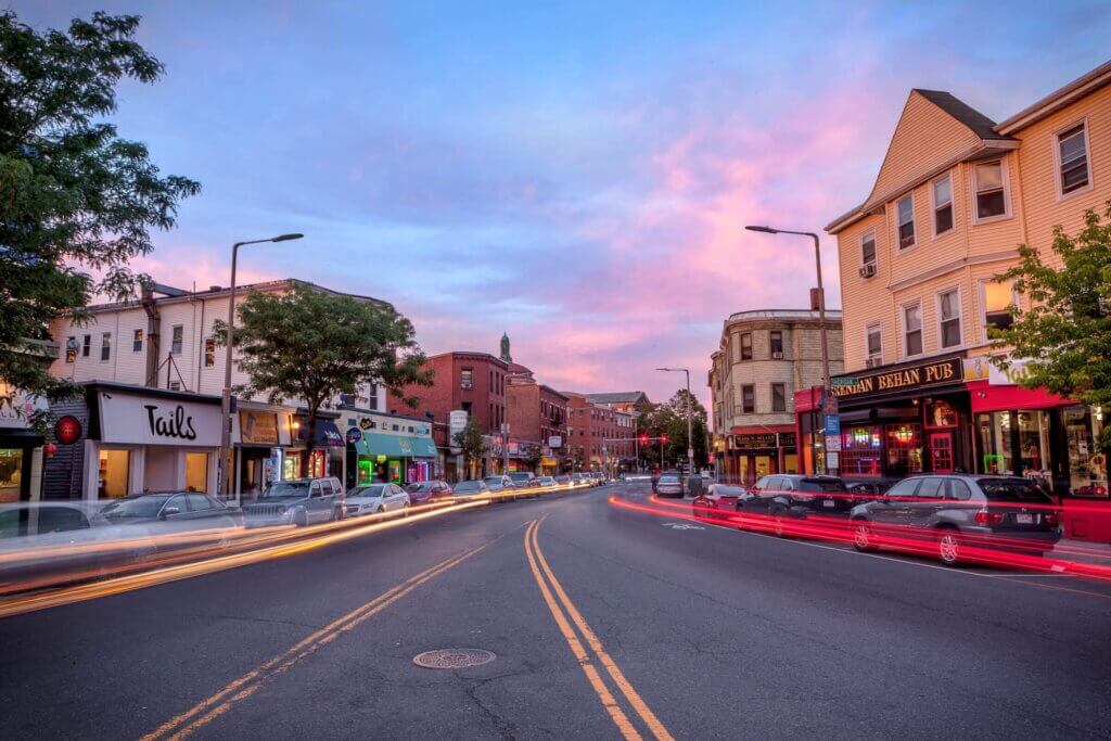 long-exposure photo from the middle of a road lined with shops and restaurants