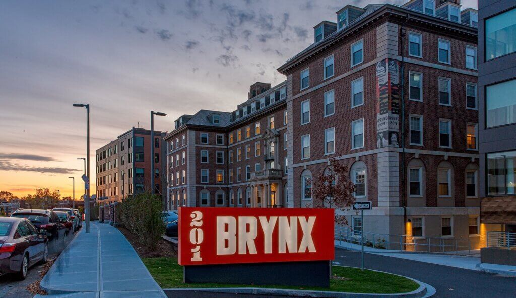 Outside view of The Brynx building at night. A modern building with sloped garden and illuminated red "221 Brynx" sign