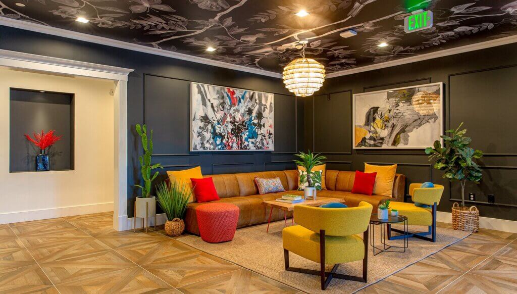 The brynx lobby furnished with L couch, chairs, plants and hanging abstract artwork