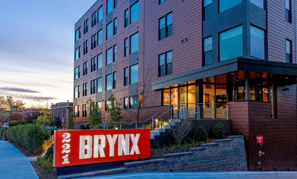 Outside view of The Brynx building at night. A modern building with sloped garden and illuminated red "221 Brynx" sign