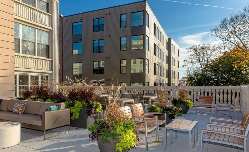 Terrace area at The Brynx furnished with multiple outdoor chairs and couches arranged in groups with large planters of plants